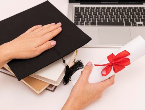 Woman holding graduation diploma certificate and graduation hat