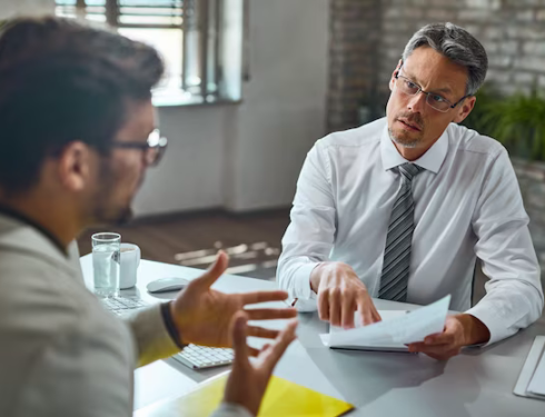 Boss talking to a candidate while looking through his resume