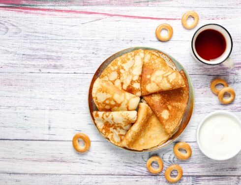 Top view of pancakes with tea and fresh cream